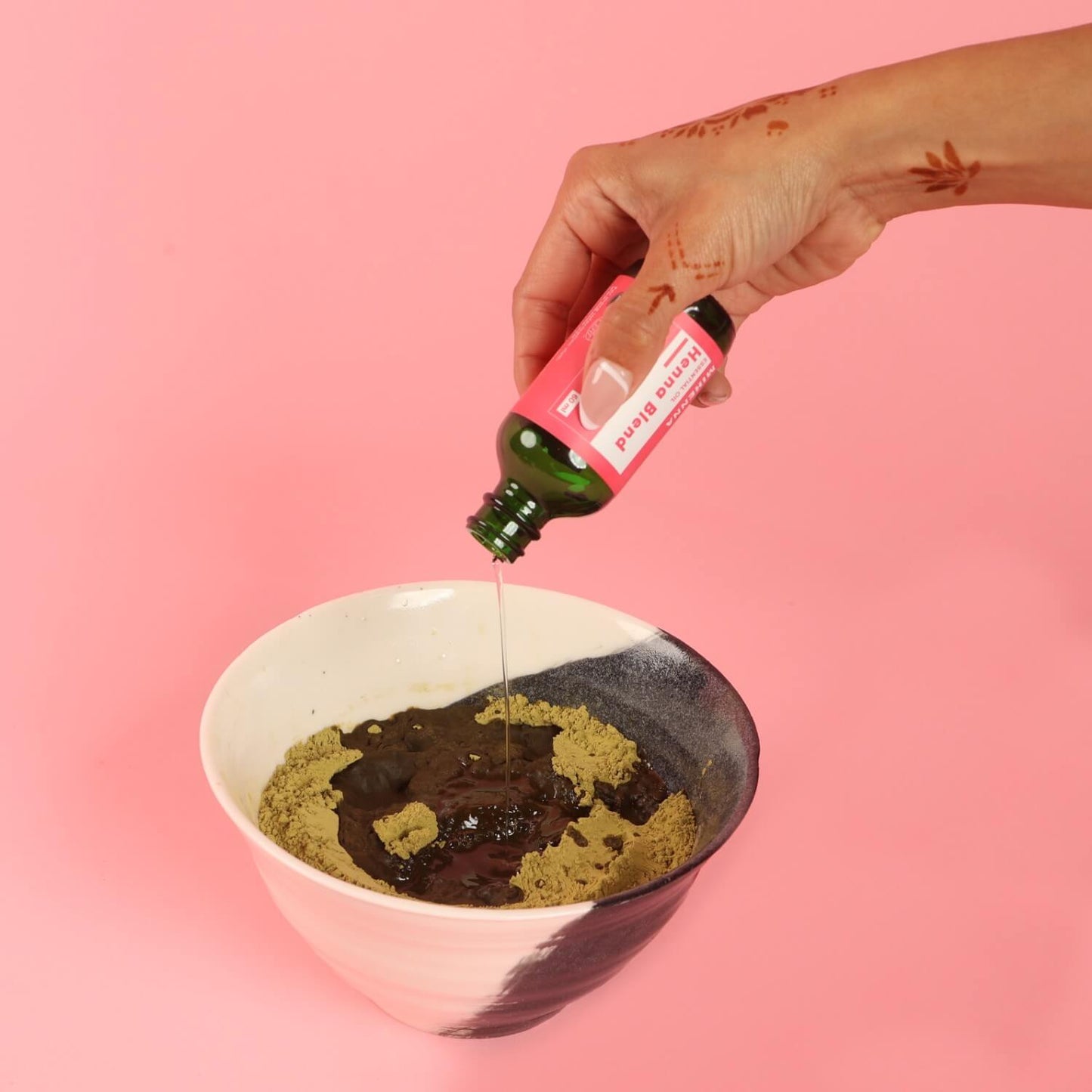 Pouring organic, custom henna blend of essential oils into henna powder
