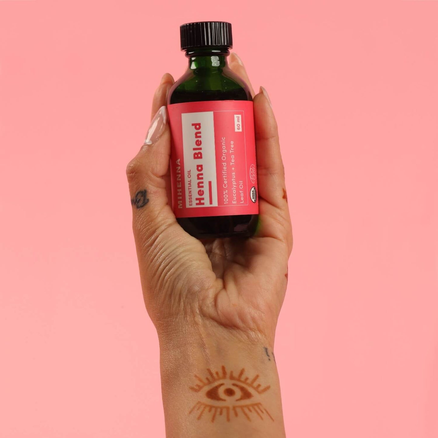Hand holding 60 ml of organic essentials oils - eucalyptus plus tea tree oil