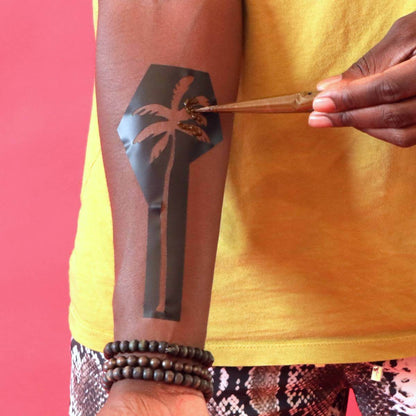 Palma - applying organic henna paste to a palm tree henna stencil on arm