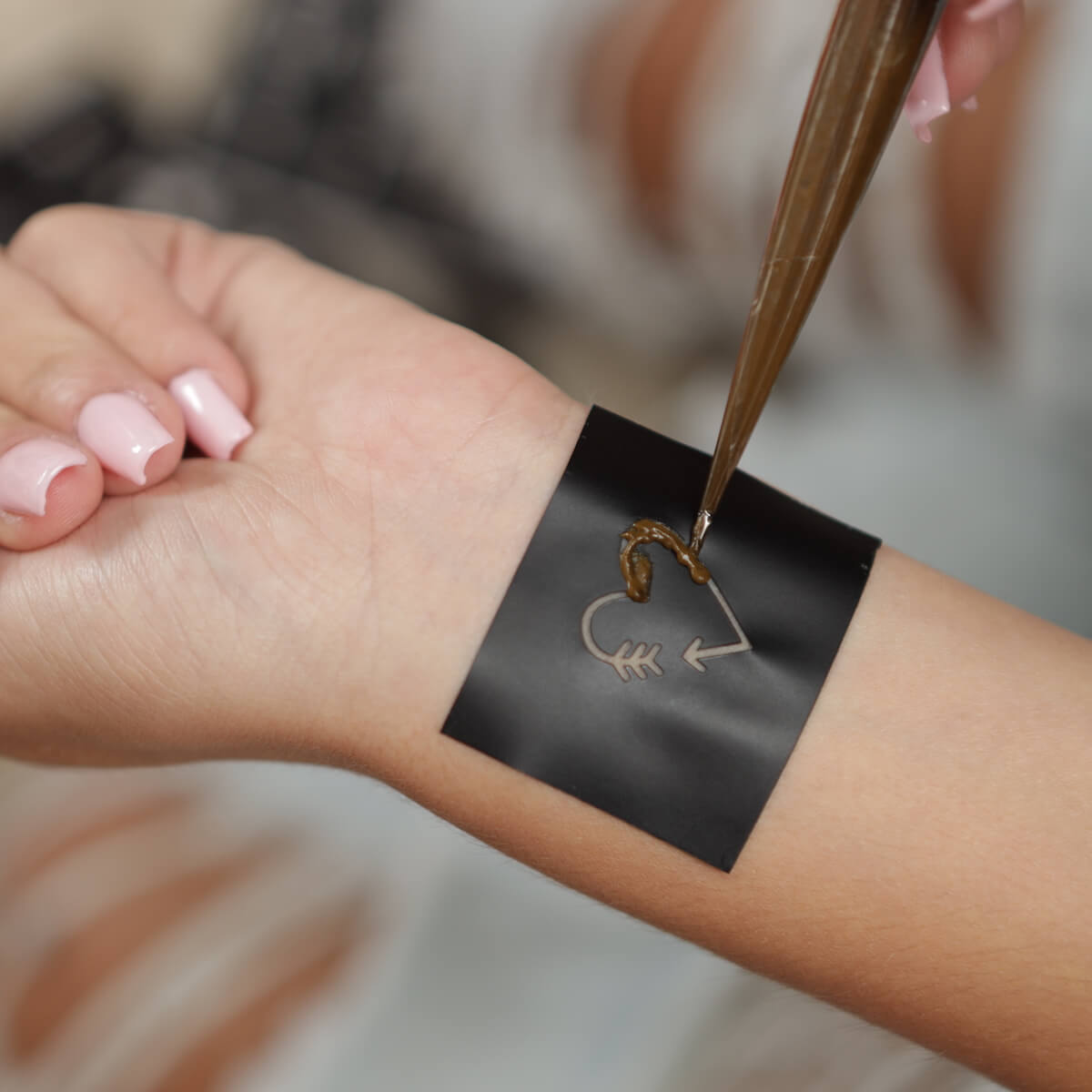 Sand - woman applying henna to mini heart temporary tattoo