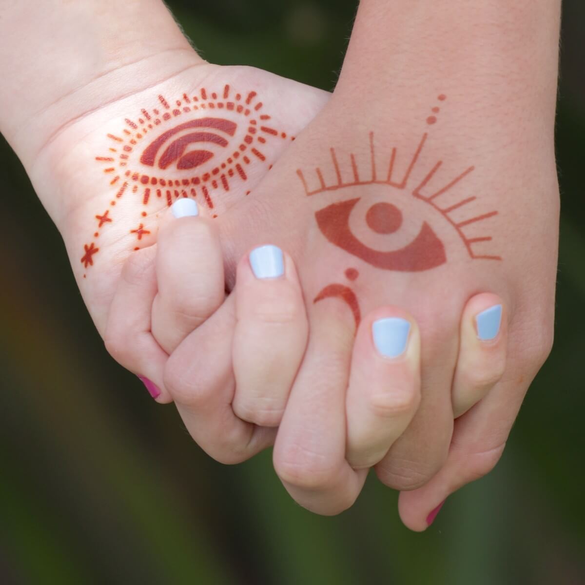 Starry Eyes - intricate eye henna tattoos on girls holding hands