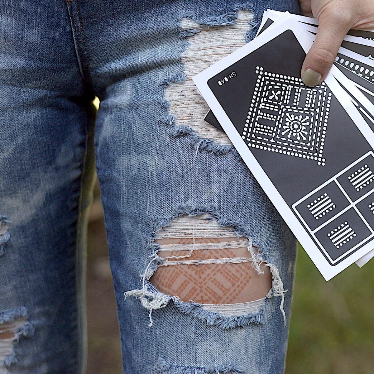 Fauzie - Woman with henna tattoo under ripped jeans and holding sticker stencils