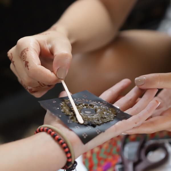 Applying henna paste to henna stencil on palm
