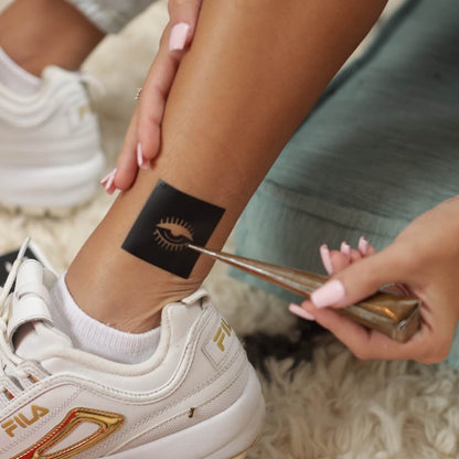 Yang - woman applying henna to mini temporary tattoos on ankle
